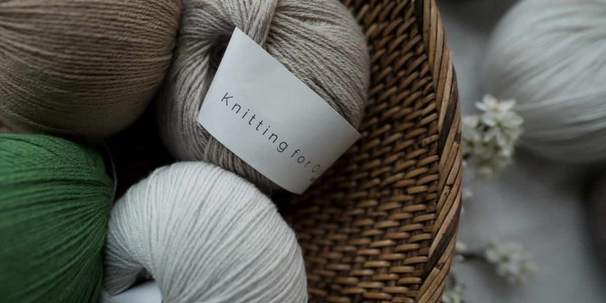 Assorted Knitting for Olive yarns in a wicker basket, highlighting natural and vibrant green shades.