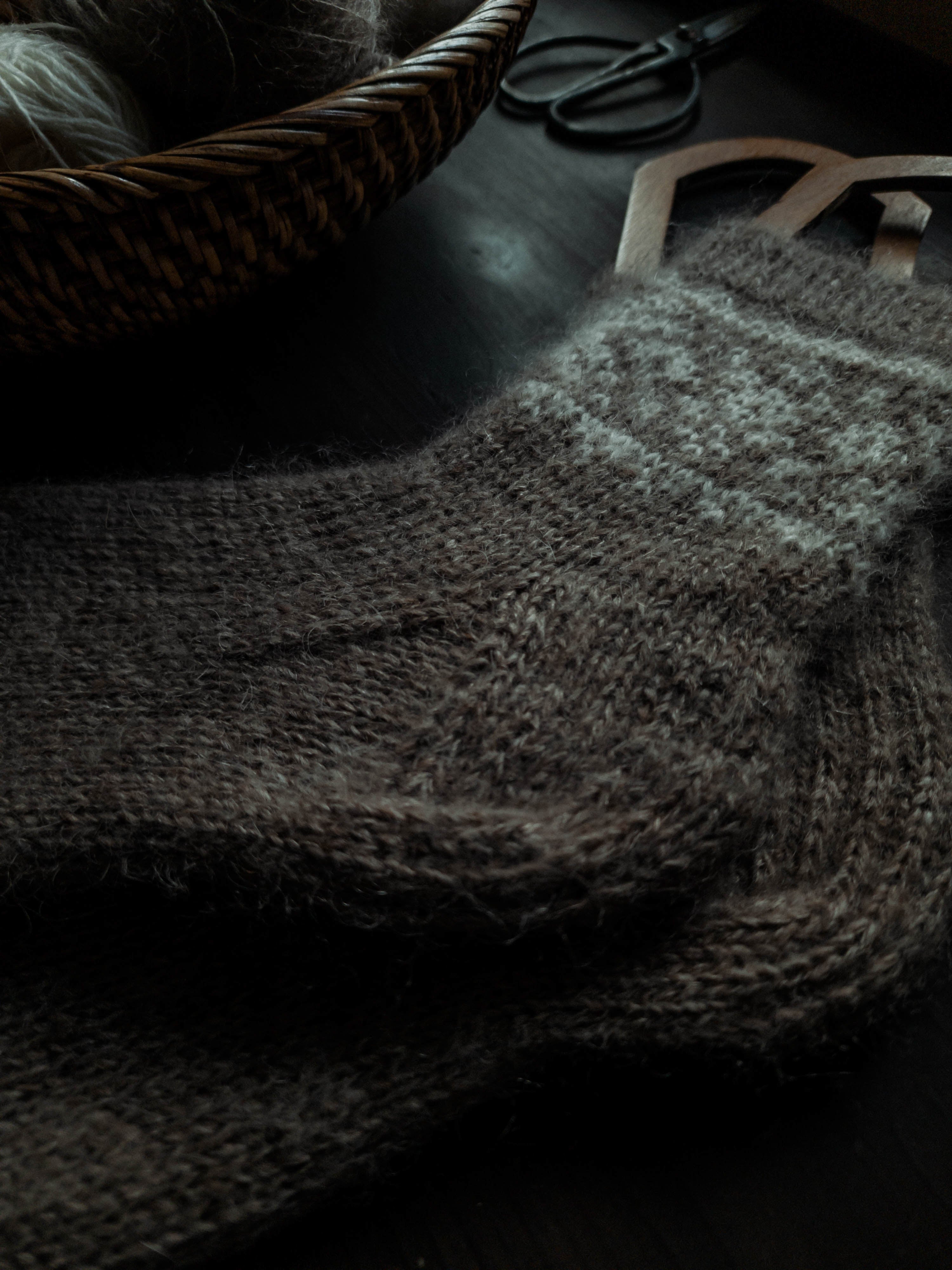 Hand-knitted beige socks surrounded by yarn and scissors.