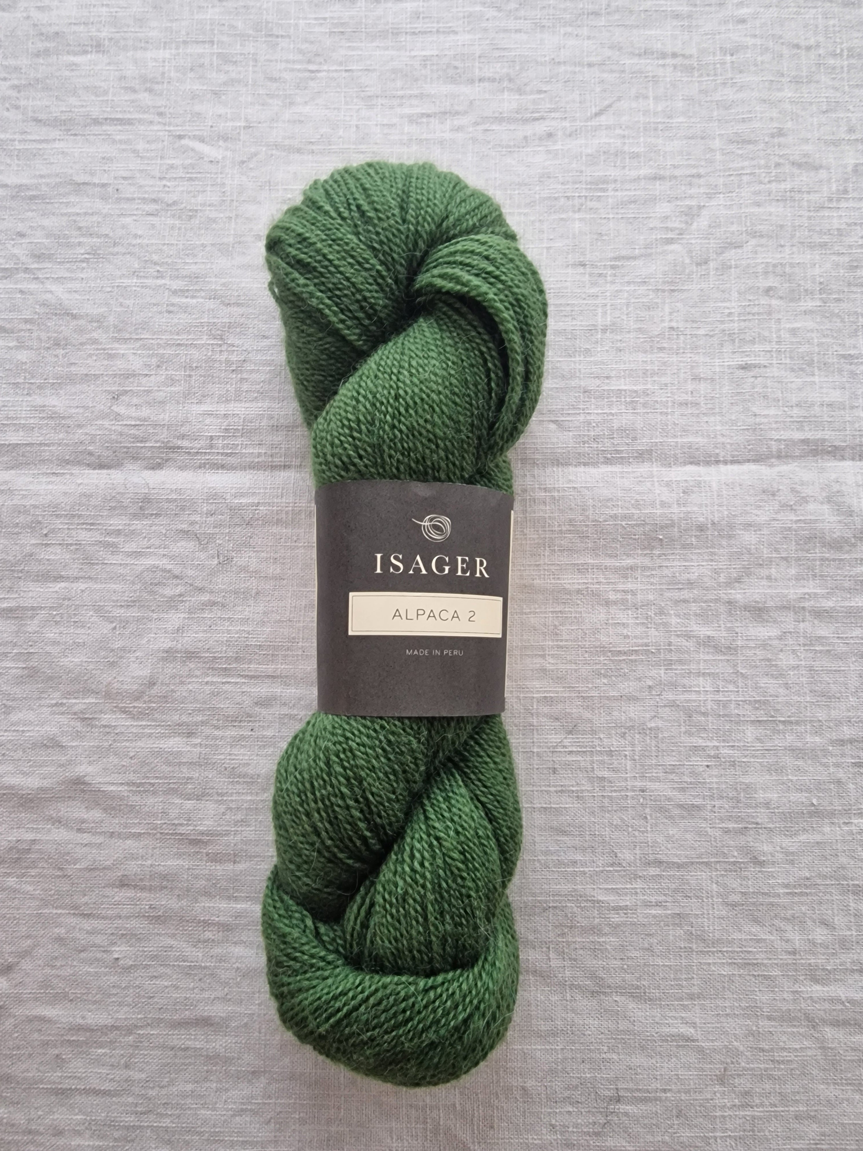 Green skein of yarn with Isager Yarns label on a gray background