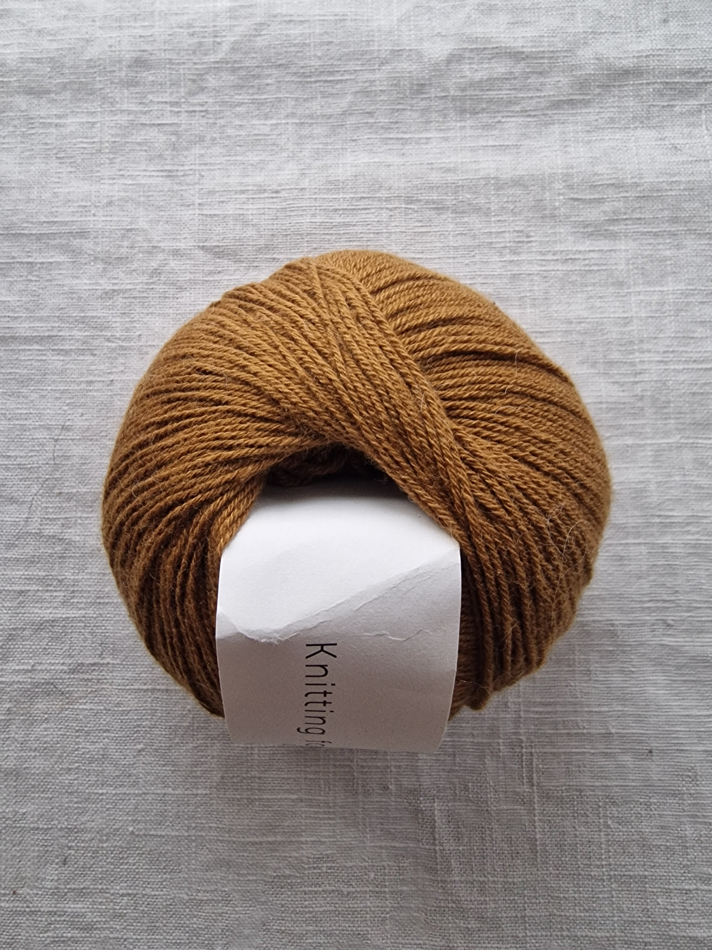 Brown skein of yarn with a 'Knitting for Olive' label on a gray background