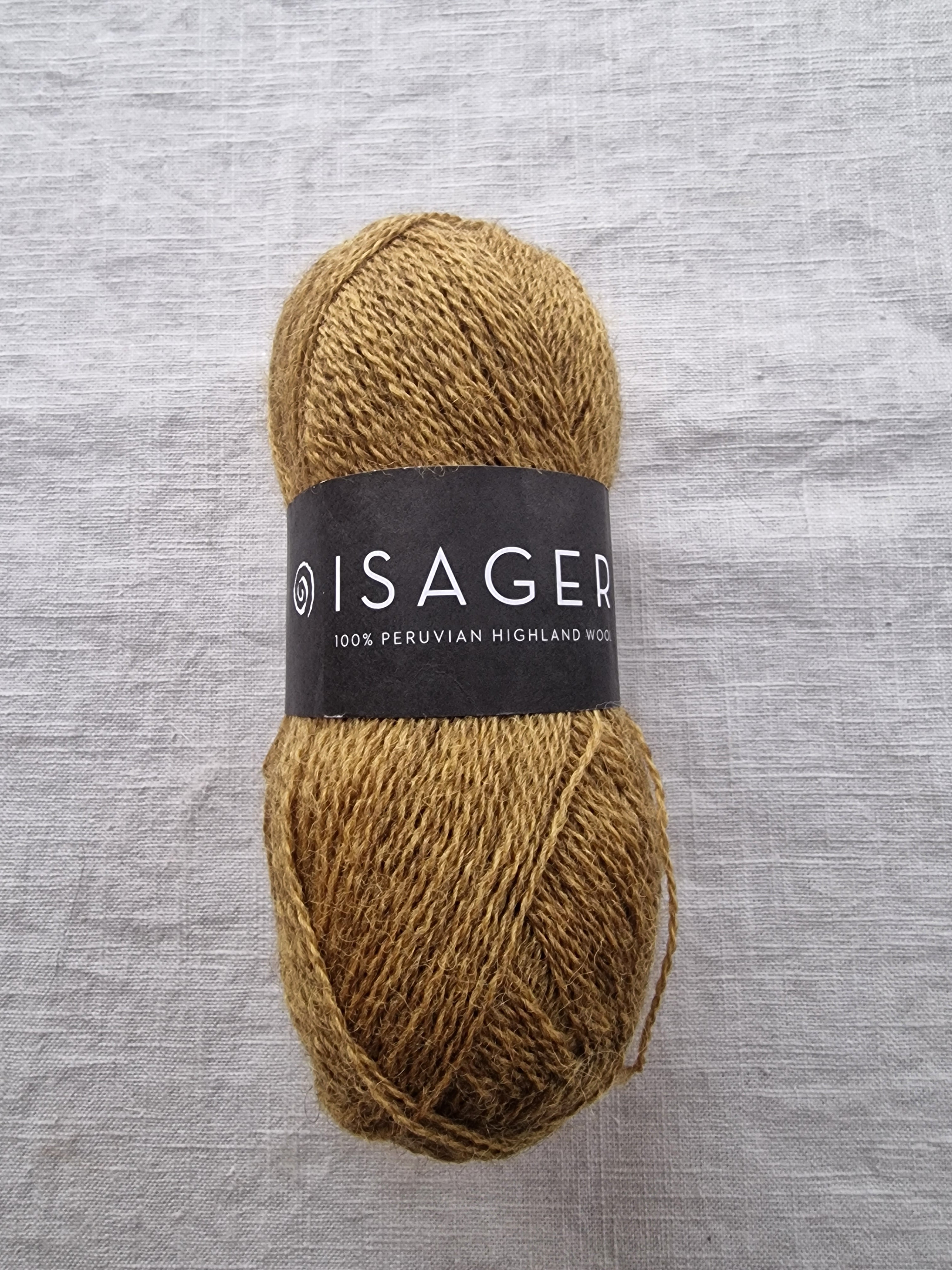 Ball of brown yarn with a label on a gray fabric background