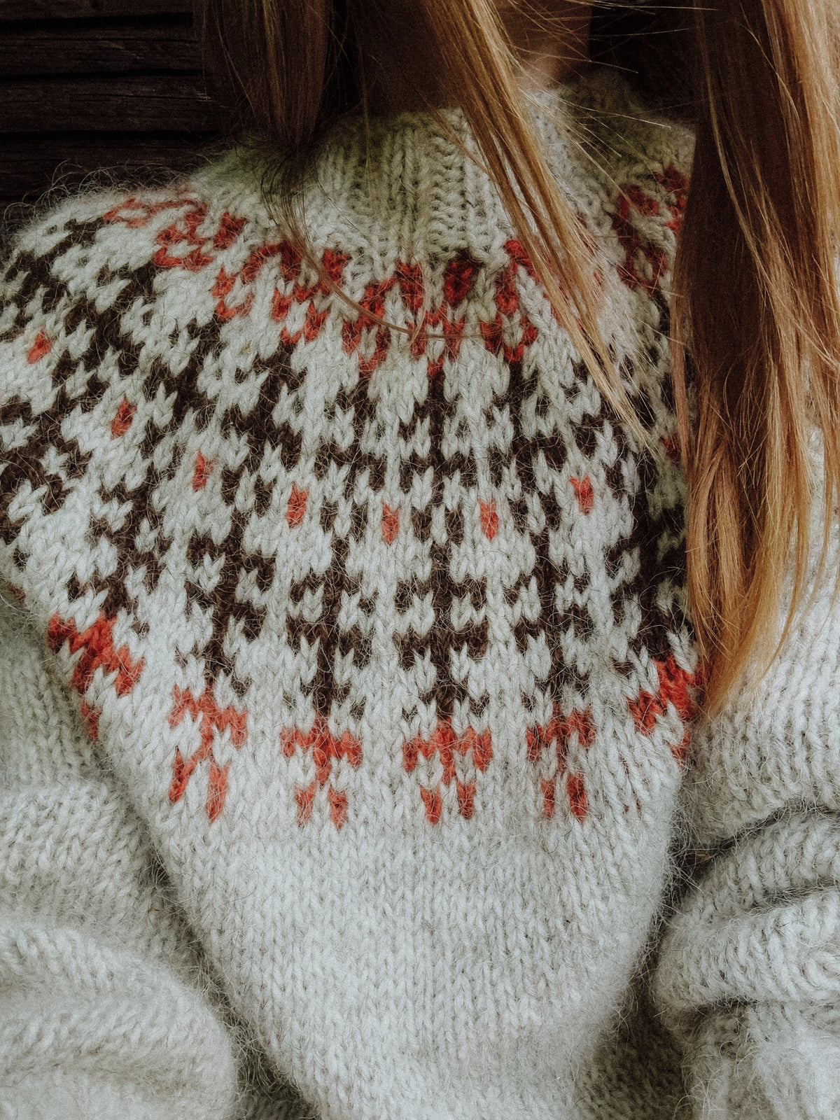 Woman wearing cream wool sweater with brown and red Fair Isle knit pattern detail on yoke.
